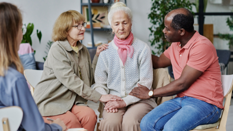 People comforting elder woman.