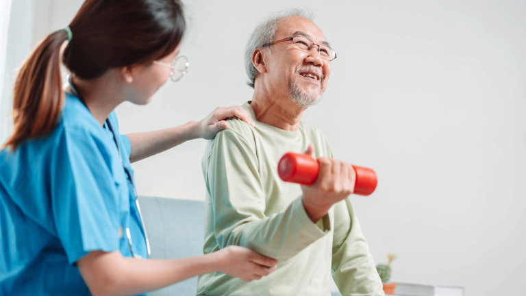 Elderly man working out with help of caregiver.